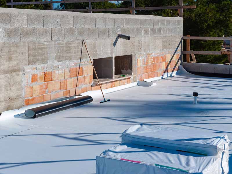 Small, flat commercial roof in the process of getting a new white, single-ply TPO/PVC sheet installed